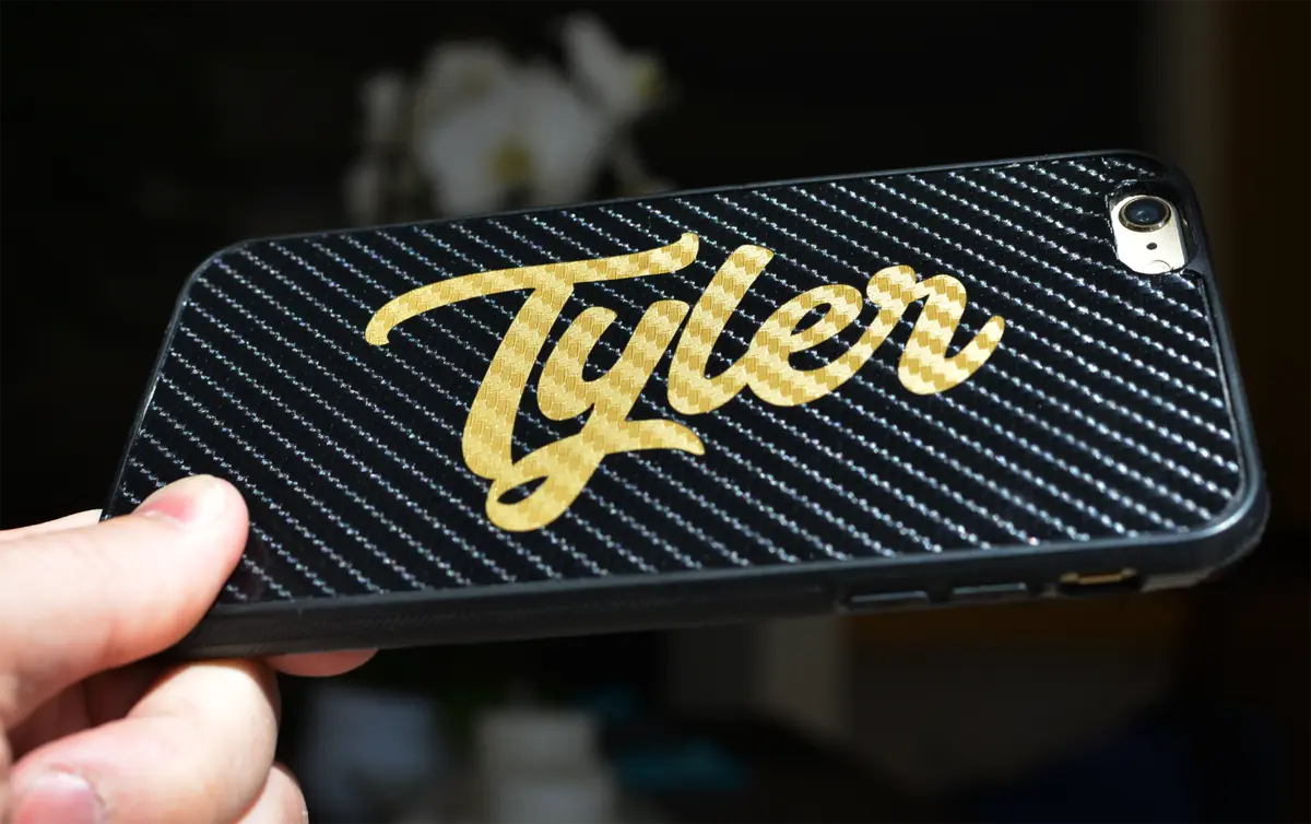 Custom gold Tyler wordmark applied to a carbon-fiber phone wrap